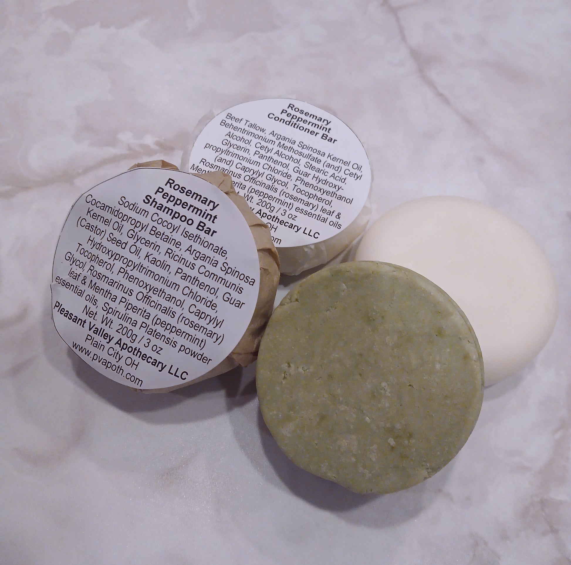 a picture of shampoo and conditioner bars , 1 set is wrapped and labeled, one set is unwrapped. shampoo bar is green and conditioner bar is white